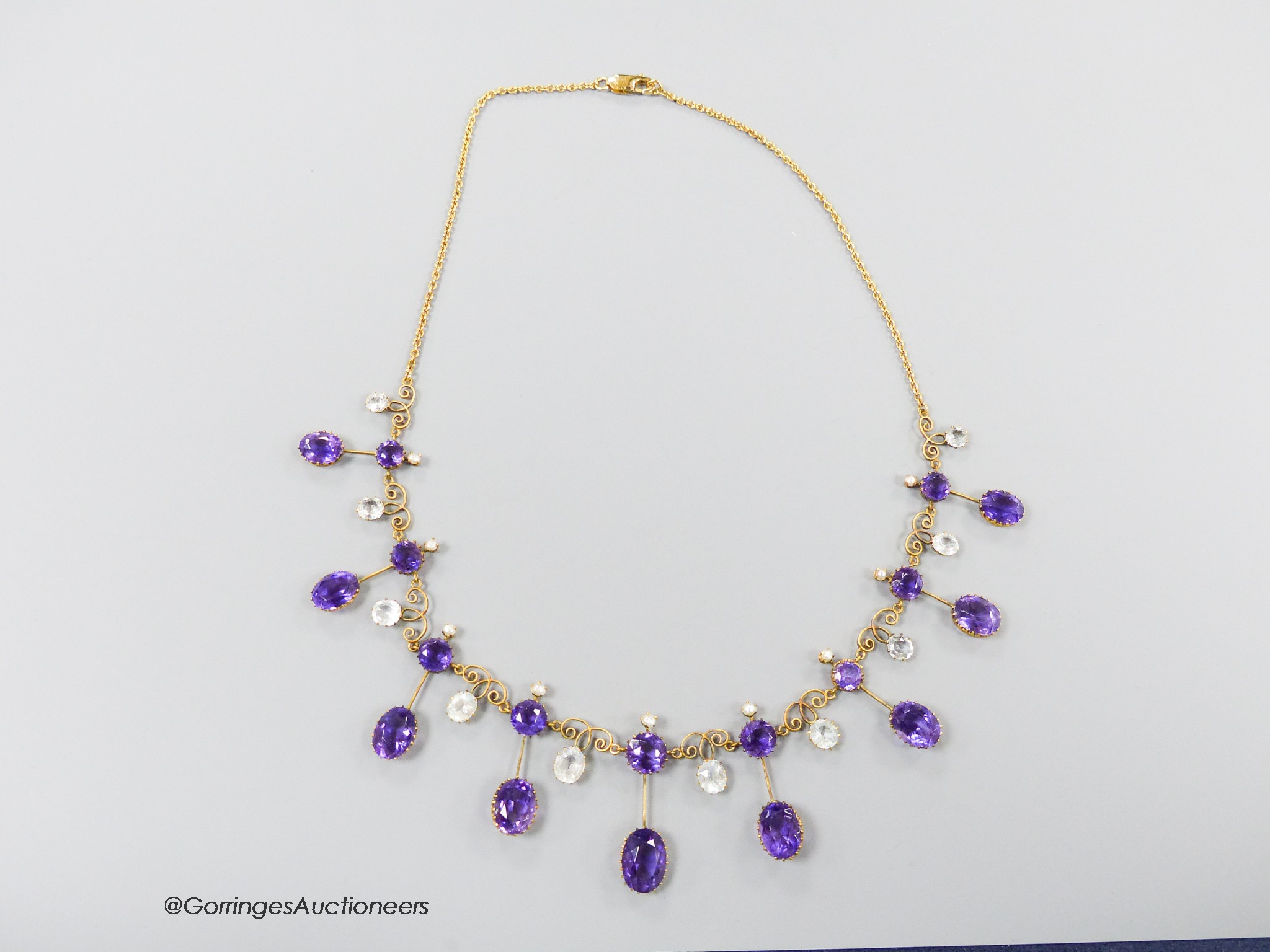 An early 20th century yellow metal, amethyst, aquamarine and seed pearl set drop fringe necklace, with later 375 clasp, 46cm, gross weight 18.6 grams.